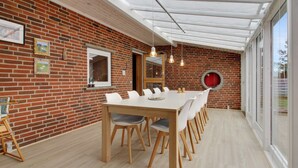 Zona pranzo moderna con parete in mattoni, tavolo e sedie in legno.