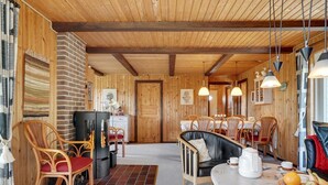 Una habitación acogedora con paneles de madera, chimenea, comedor y una mesa servida con fruta.
