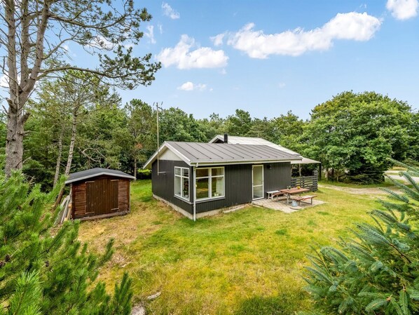 A small cabin with a fenced yard, a separate shed, and a picnic table.