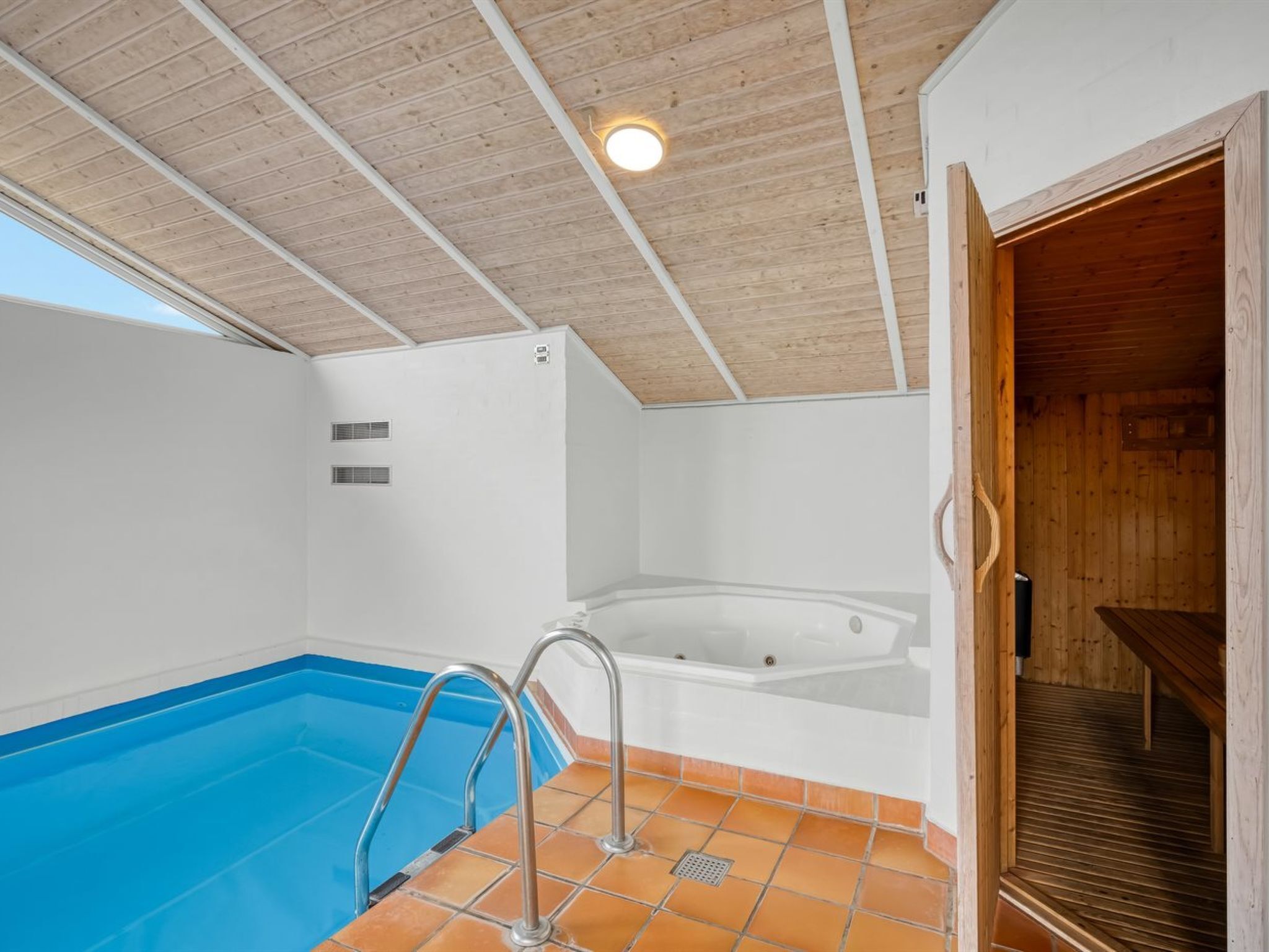 A swimming pool with a wooden ceiling and a jacuzzi.