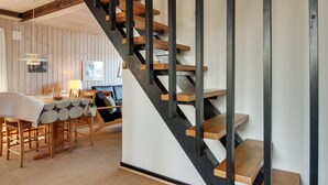 Un interior moderno con escalera de madera, comedor y cocina.