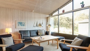 Una sala de estar moderna con techo de madera, un ventanal y vistas al exterior.
