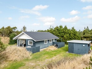 A house with a covered porch, a fenced yard, and a small shed.