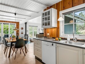 A modern kitchen with white cabinets, a Bosch dishwasher, a large window, and a dining area with a table and chairs.