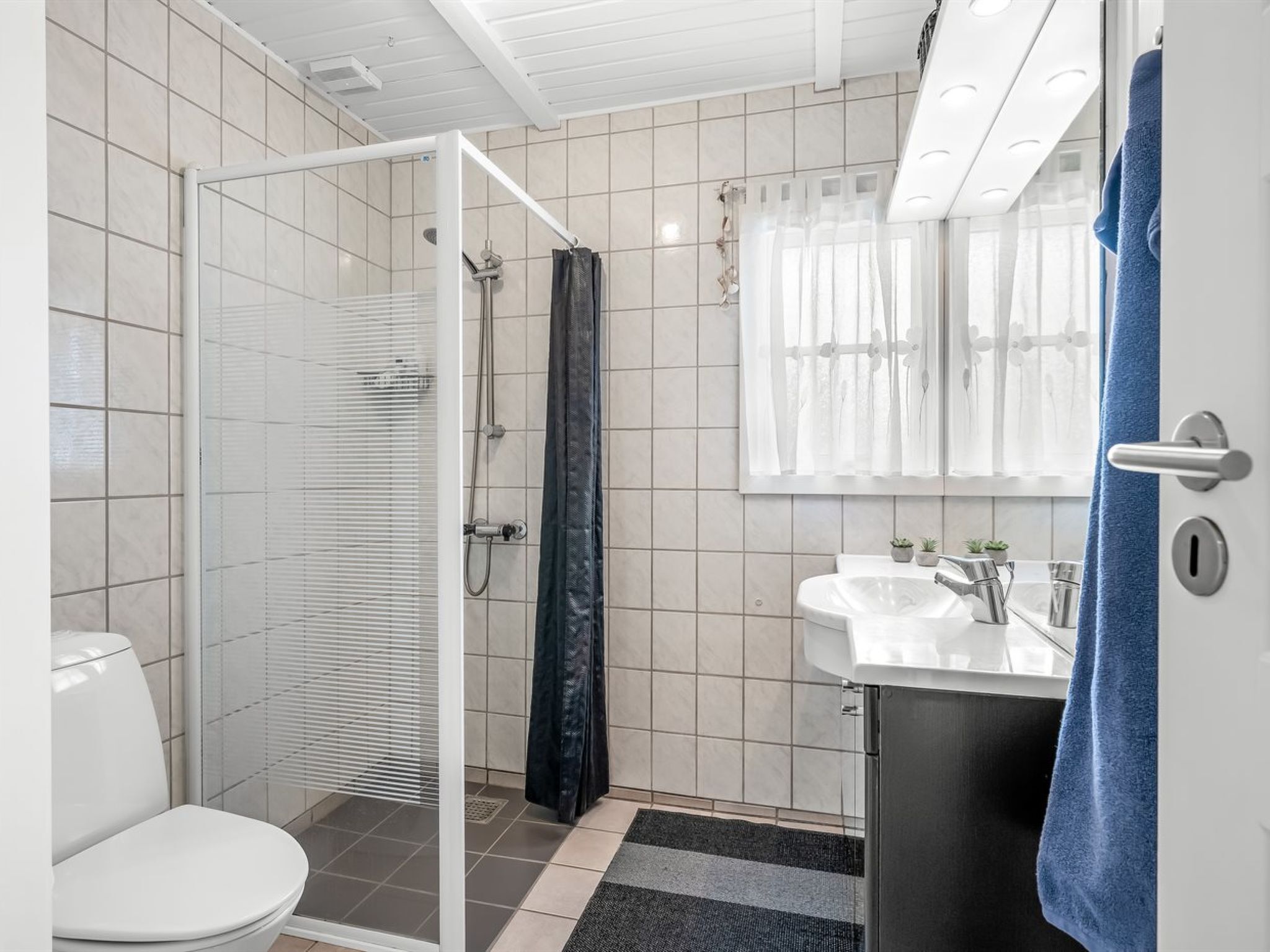 A bathroom with a toilet, shower, and sink.