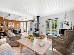 Un salon moderne avec une cheminée, des meubles en osier et une grande fenêtre.