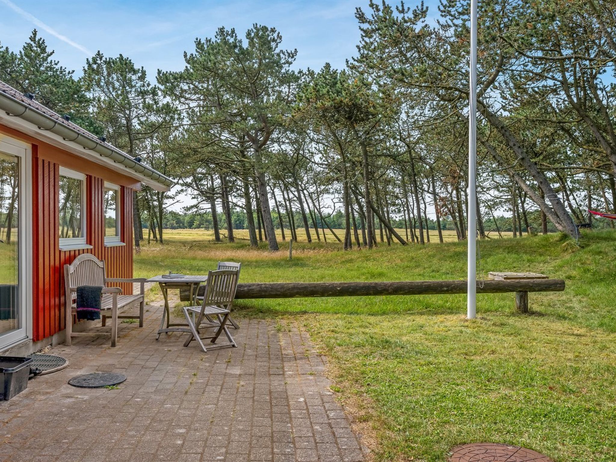A patio with outdoor furniture, a wooden table, and chairs.