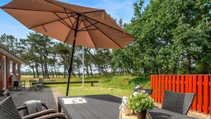 Un patio al aire libre con mesa, sillas y una sombrilla grande.