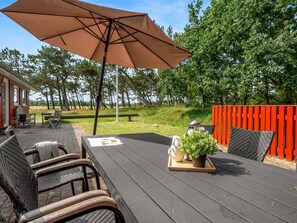 Un patio al aire libre con mesa, sillas y una sombrilla grande.