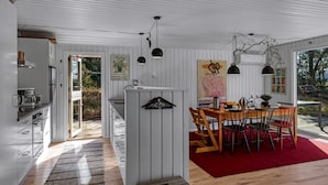 Una cocina moderna con armarios blancos, un área de comedor con un tapete rojo y vistas al exterior.