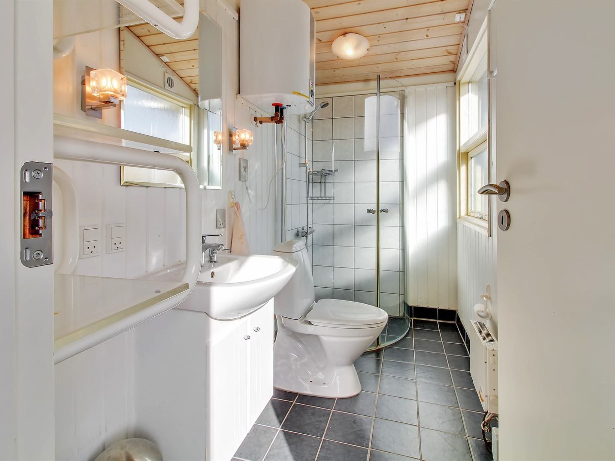 Une salle de bain compacte avec un lavabo blanc, des toilettes et une cabine de douche en verre.