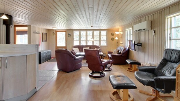 Un vaste espace de vie agrémenté de boiseries, d’une cheminée, de canapés en cuir et d’un plancher en bois.
