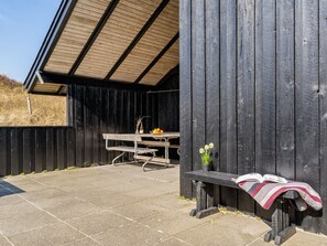 Een rustiek houten gebouw met een bankje en een tafel buiten.