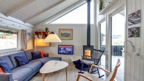 A cozy living room with a sofa, coffee table, and chairs, a TV, a fireplace, and a large window. - "Auli" - 200m from the sea by Interhome (Vejers Strand)
