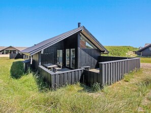 Une cabane moderne en bois, dotée d’un toit en pente, de grandes fenêtres et d’une terrasse.