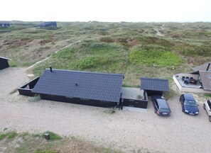 Een modern gebouw met een plat dak, een grindpad en een auto ervoor geparkeerd.