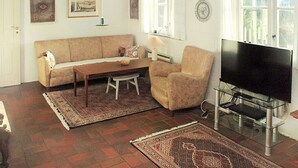 A living room with a sofa, armchair, coffee table, TV, and rugs. - "Zuzan" - 500m from the sea by Interhome (Vejers Strand)