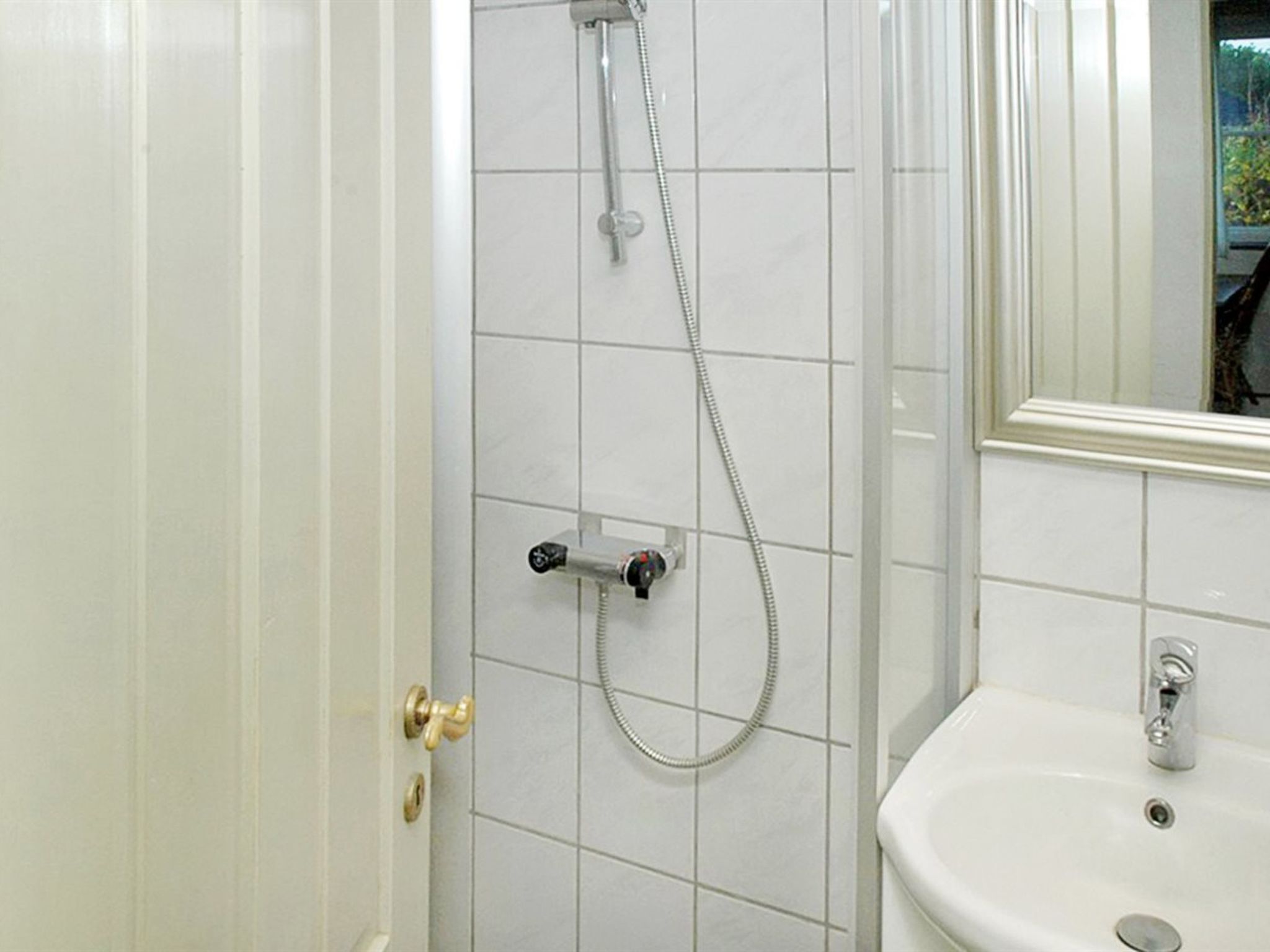 A bathroom with a shower, a sink, and a mirror.