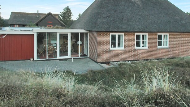 A house with a thatched roof, a red garage, and a glass door leading to a patio area. - "Zuzan" - 500m from the sea by Interhome (Vejers Strand)