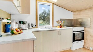Eine moderne Küche mit Fenster, weißen Schränken, einer Spüle, einem Wasserkocher und einem Herd.