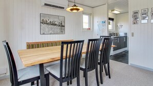 A dining area with a wooden table and black chairs, a pendant light, and a wall-mounted picture.
