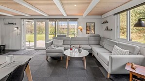 A modern living room with a grey sectional sofa, a round coffee table, and a dining area with a table and chairs.