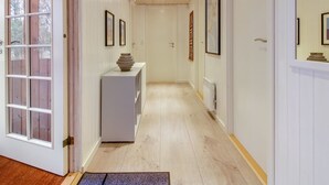 A hallway with white walls, wooden flooring, and a white door with glass panels.