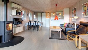 Ein gemütliches Wohnzimmer mit Kamin, einem Essbereich und einer Küche im Hintergrund.