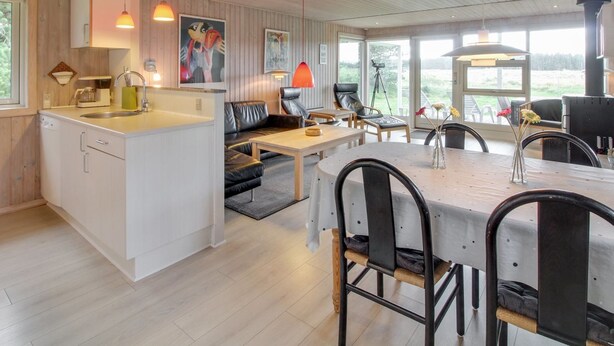 Eine moderne Küche mit Kochinsel, Essbereich mit Stühlen und einer Sitzecke mit Sofa.