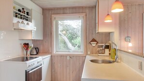 Eine moderne Küche mit Holzwänden, einem eingebauten Backofen, einer Spüle und Pendelleuchten.