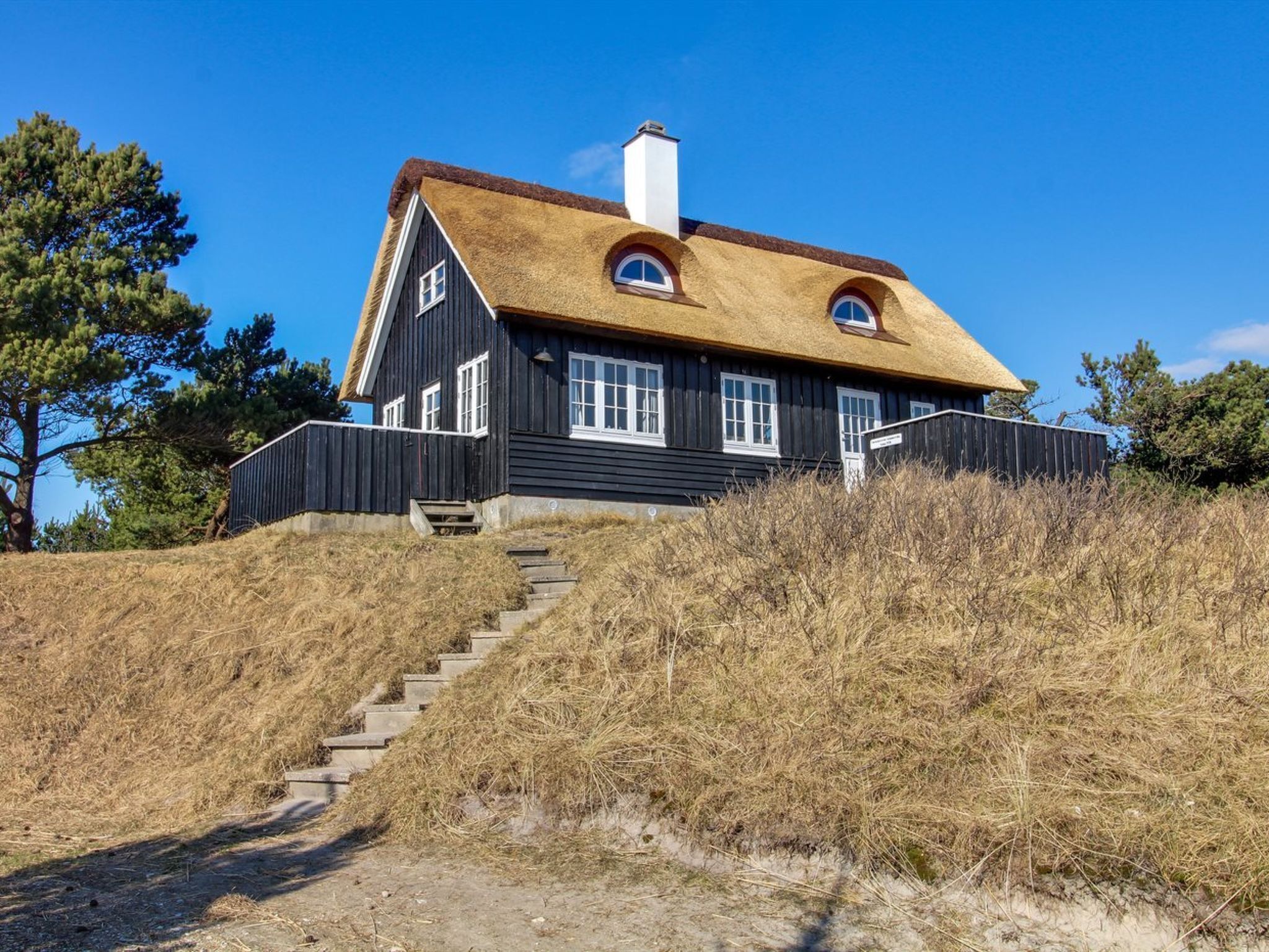 A house with a steeply pitched roof, a chimney, and a staircase leading to the entrance.