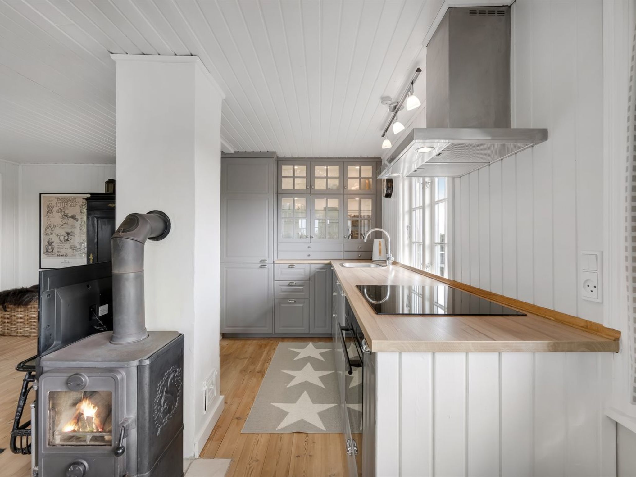 A modern kitchen with white cabinetry, a built-in stove, and a wooden island with a sink.