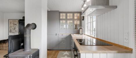 A modern kitchen with white cabinetry, a built-in stove, and a wooden island with a sink.