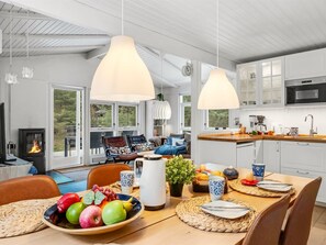 A modern kitchen with white cabinets, a built-in oven, and a dining area with a wooden table set for two.