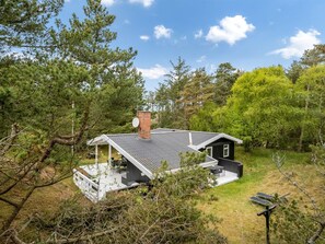 Une maison moderne dotée d’un porche abrité, d’une cheminée et de panneaux solaires.