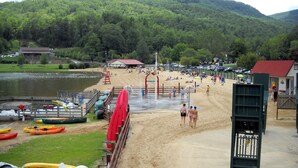 Une plage avec des kayaks, une tour de surveillance pour les sauveteurs et une montagne en arrière-plan.