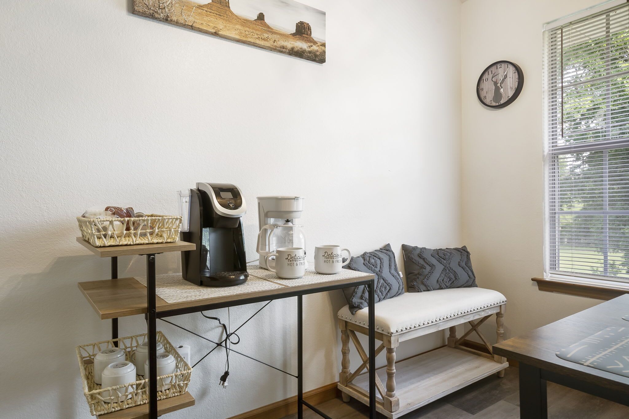 Une pièce chaleureuse avec un coin café, un banc et une horloge au mur.