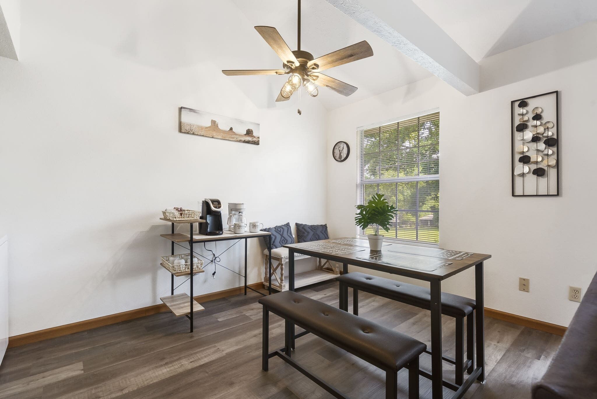 Una cocina moderna con comedor, que incluye un ventilador de techo, una ventana con persianas y un reloj de pared.