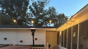 Un terrazzo in legno con idromassaggio, un pergolato con luci a catena e un'area porticata.