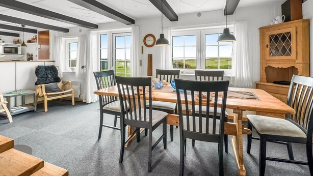 Una cucina moderna con zona pranzo, caratterizzata da un grande tavolo di legno, sedie nere e vista sull'esterno.