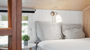 Une chambre à coucher avec un lit, une table de chevet, une lampe et une fenêtre donnant sur un paysage verdoyant.