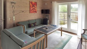 A cozy living room with a sofa, a coffee table, and a television on a wooden wall.
