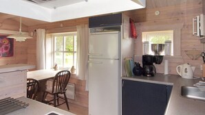 A compact kitchen with a refrigerator, stove, and coffee maker.