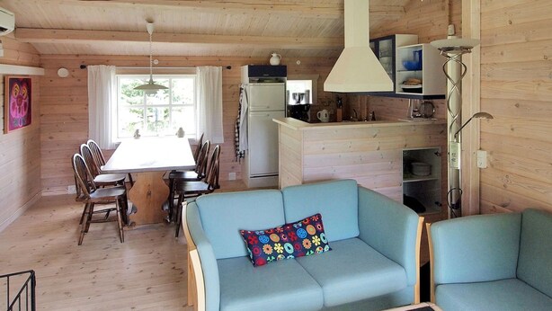 A cozy cabin interior with a dining area, a kitchenette, and a seating area with a sofa and chairs.