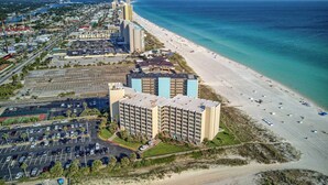 A beachfront hotel with multiple floors, a parking lot, and a beach view.