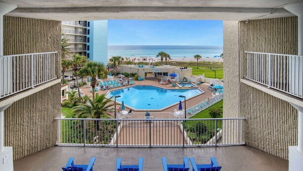 A balcony with a view of a pool and beach.