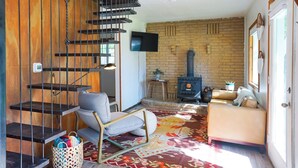 Ein modernes Wohnzimmer mit Treppe, Kamin und Fernseher.