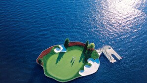Luftaufnahme einer Golfplatzinsel mit Sandbunkern und einer Holzbrücke.