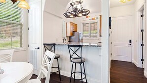 Cocina con una isla blanca, dos taburetes de bar e iluminación colgante.