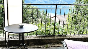 A balcony with a table and a cushion, overlooking a mountainous landscape. - Just Restored close to Franklin College and Lugano (Montagnola)
